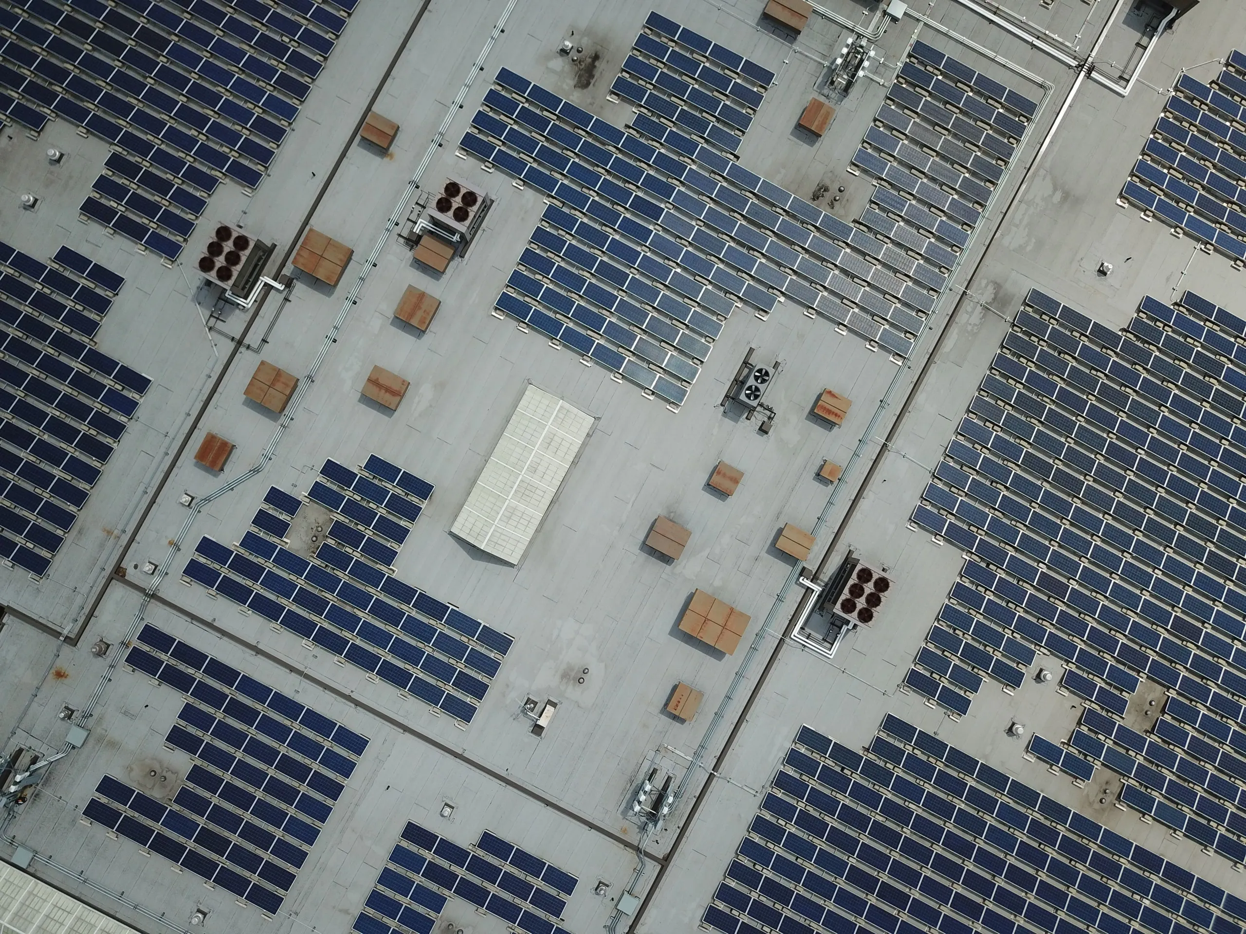 Vue aérienne d'une toiture industrielle couverte de rangées de panneaux solaires.